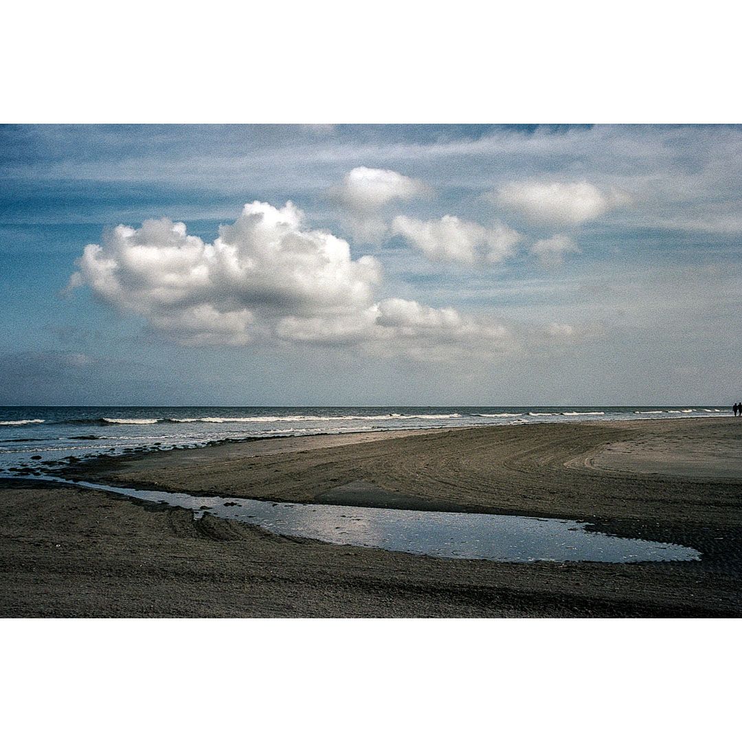 Colour photo of the North Sea and beach under a cloudy sky on the Wadden Sea island Schiermonnikoog in The Netherlands, taken during a Wadden Sea coast hike in August 2025.
